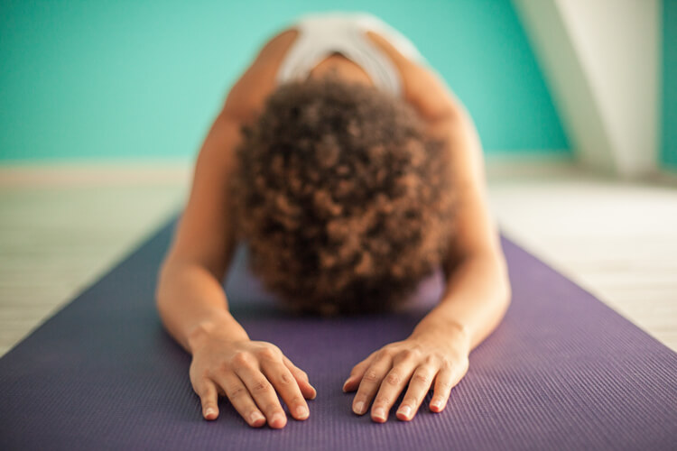 Mujer haciendo postura de yoga gurpranam